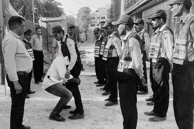 Officers in high-visibility vests at a construction site, watching an instructor demonstrate a lifting technique